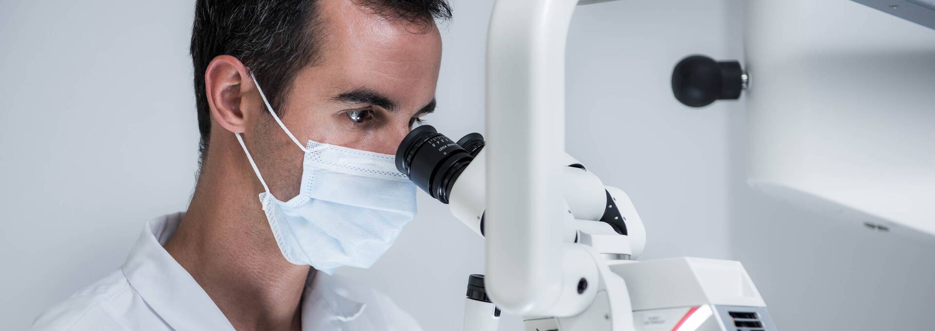 Zahnarzt fokussiert am Dentalmikroskop Zahnarzt fokussiert am Dentalmikroskop